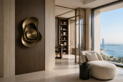 Warm brass brass wall sculpture Conca, a deep spun basin with a broad everted rim, on a plaster wall.