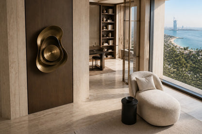 Warm brass brass wall sculpture Conca, a deep spun basin with a broad everted rim, on a plaster wall.