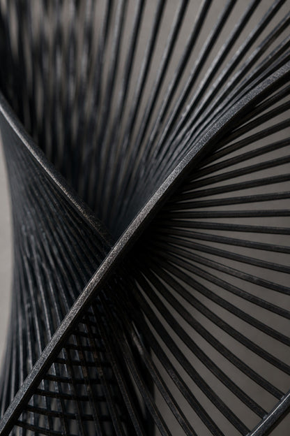 Graphite steel wall sculpture Iltifat, a single sheet folded through itself in one continuous turn, on a plaster wall.