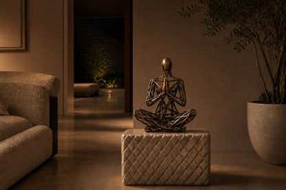 Bronze strut-cage seated figure sculpture Intreccio in lotus with hands together, on a quilted travertine block.