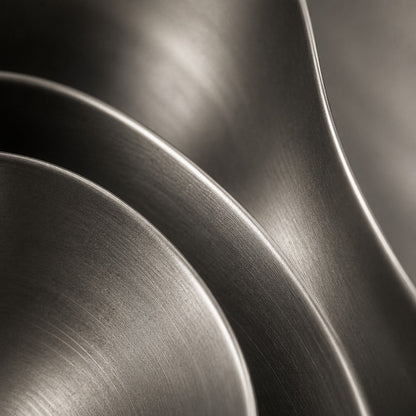 Iron grey bronze wall sculpture Roca, a cast boulder form mounted proud of a spun disc, on a plaster wall.
