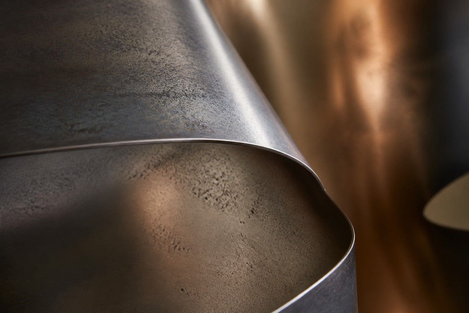 Dark bronze bronze wall sculpture Ponte, two cantilevered spans meeting at a knotted centre, on a plaster wall.