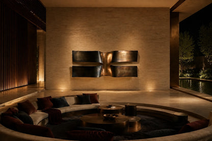 Dark bronze bronze wall sculpture Ponte, two cantilevered spans meeting at a knotted centre, on a plaster wall.
