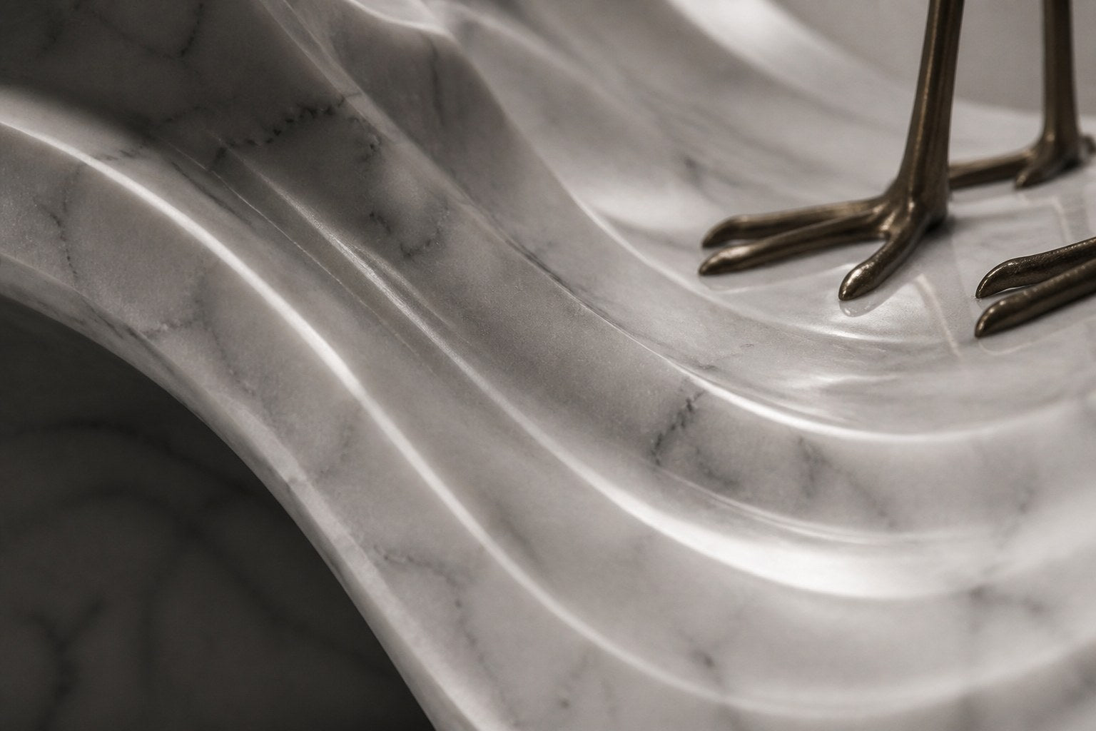 White marble wave sculpture Juncal in four crests with a slender bronze figure standing at the high point, on a dark granite oval base.