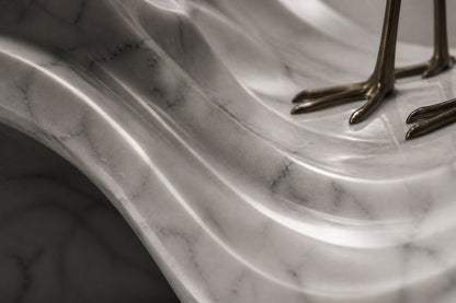 White marble wave sculpture Juncal in four crests with a slender bronze figure standing at the high point, on a dark granite oval base.