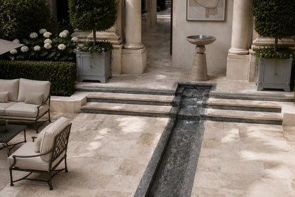 Stone pedestal fountain Kathib Ø65, pale warm stone, on a pale stone floor.
