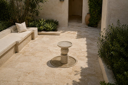Stone pedestal fountain Kathib Ø65, pale warm stone, on a pale stone floor.