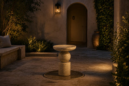 Kathib Ø65 stone pedestal fountain, lit after dark, the falling water catching the light