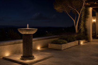 Dark marble pedestal fountain Layla Ø65, deep black with white veining, on a pale stone floor.
