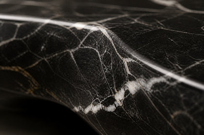 Black marble with white veining fire table Laylan 220, deep black with white and gold veining, on a pale stone floor.