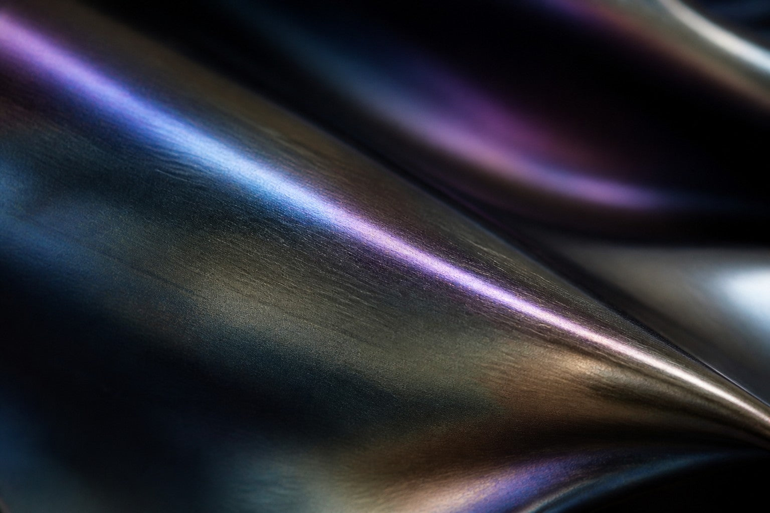 Iridescent blue and violet steel wall sculpture Lazward, overlapping scales layered on a shaped armature, on a plaster wall.