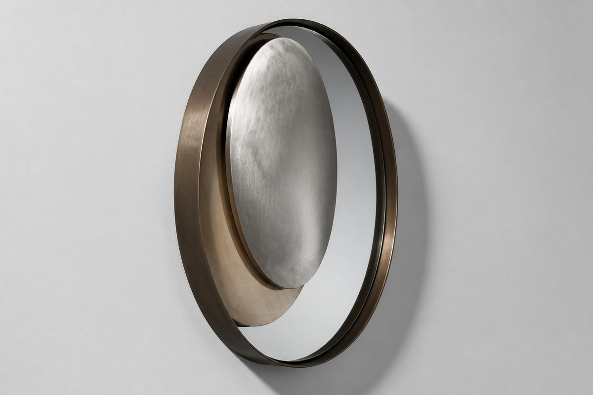 Lente — Ø 200 cm bronze ring mirror with an off-centre brushed steel lens, studio side angle showing its depth
