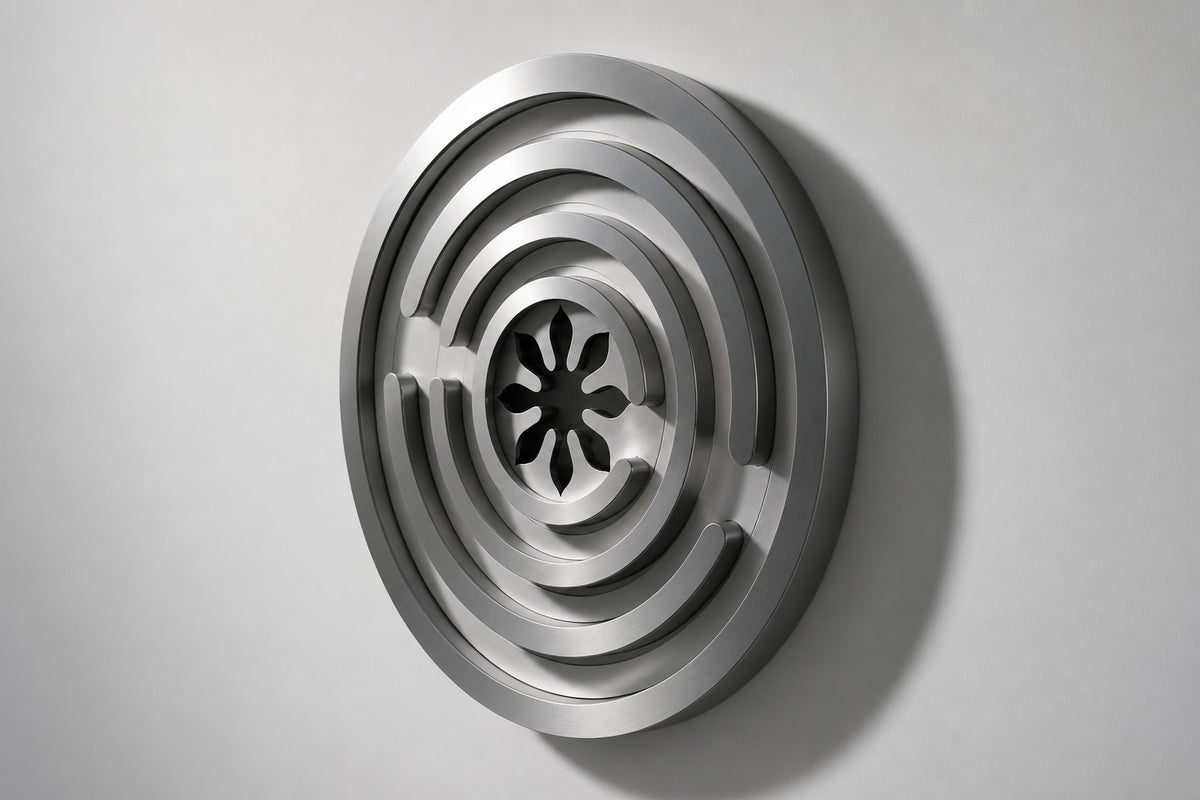 Meandro — Ø 200 cm brushed stainless steel circular wall relief with a labyrinth of arcs, studio side angle showing its depth
