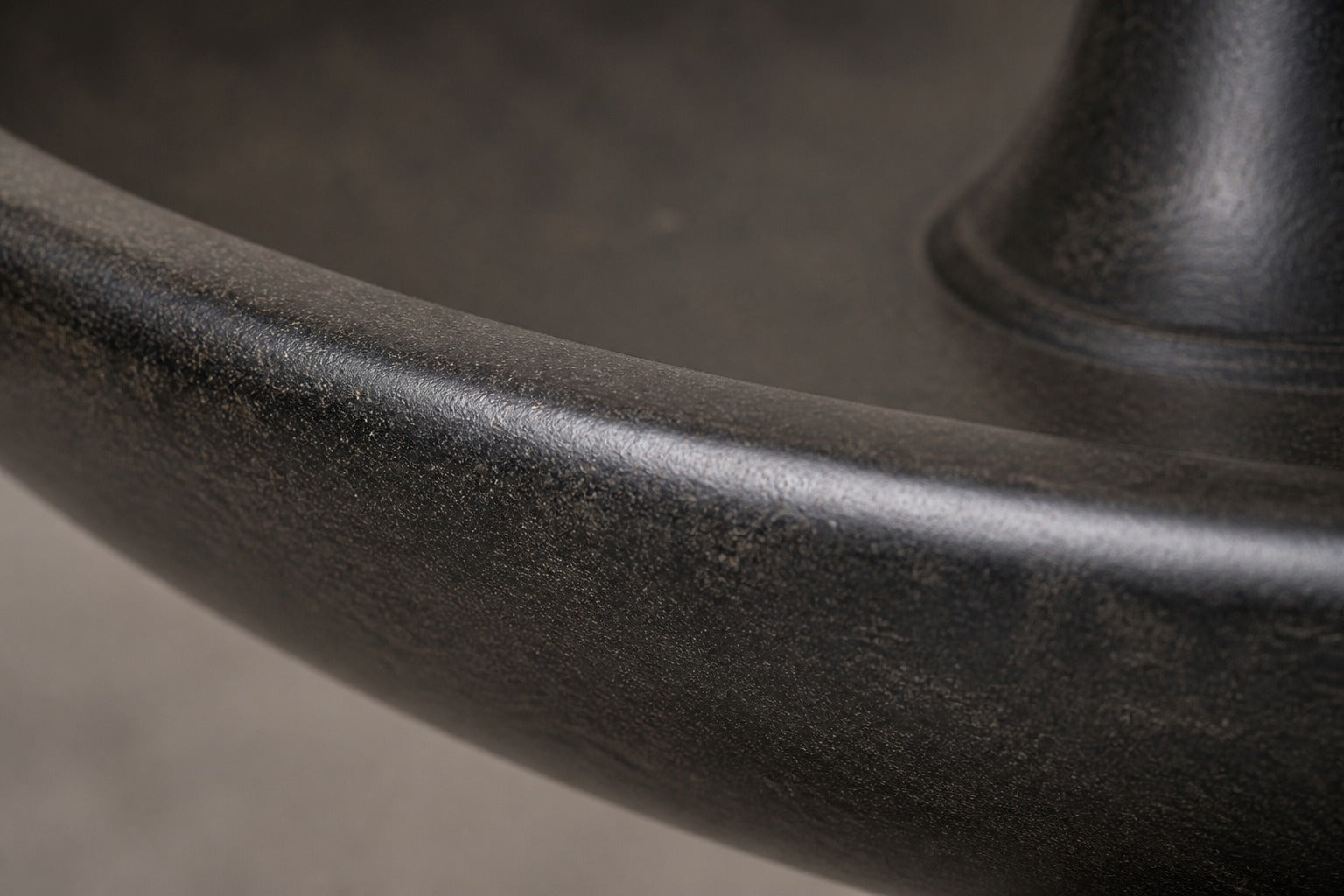 Stone pedestal fountain Mirala Ø65, dark charcoal, on a pale stone floor.