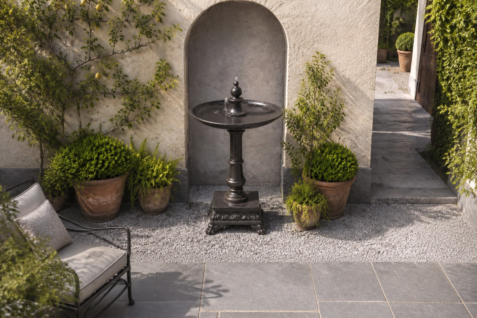 Stone pedestal fountain Mirala Ø65, dark charcoal, on a pale stone floor.