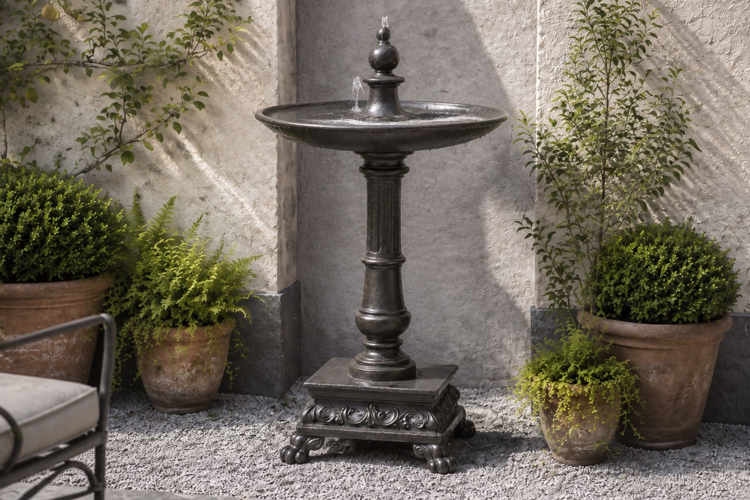 Stone pedestal fountain Mirala Ø65, dark charcoal, on a pale stone floor.