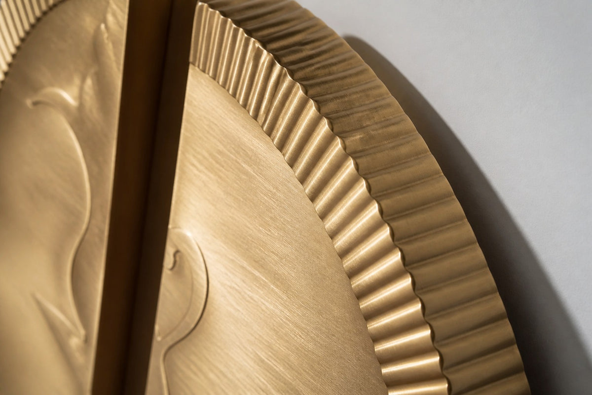 Mitad — Ø 200 cm brushed brass circular wall relief split into two offset fluted halves, close studio detail of the surface and material