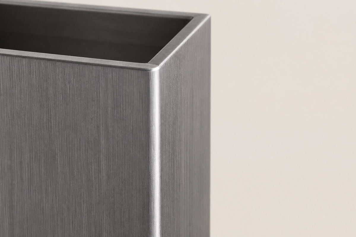 Monolith Brushed Stainless Steel Column Planter — 140 cm slim brushed stainless steel column planter with a trailing plant, close studio detail of the surface and material