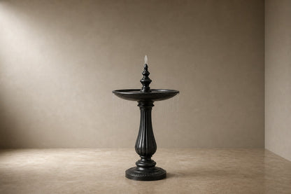 Stone pedestal fountain Nadira Ø65, matte near-black, on a pale stone floor.