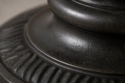 Stone pedestal fountain Nadira Ø65, matte near-black, on a pale stone floor.
