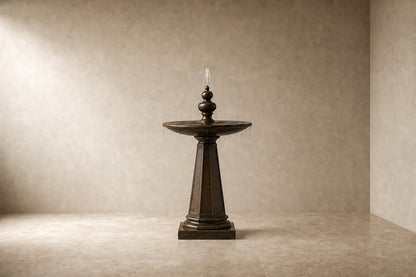 Stone pedestal fountain Namika Ø65, warm mottled brown, on a pale stone floor.
