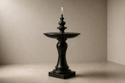Stone pedestal fountain Nasima Ø65, black with gold and amber veining, on a pale stone floor.