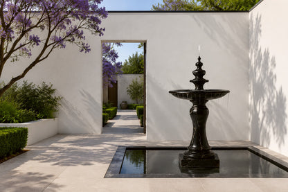 Stone pedestal fountain Nasima Ø65, black with gold and amber veining, on a pale stone floor.