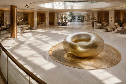Woven brass wire torus sculpture Nunki Ø120, reading as solid gold where the mesh doubles and open gauze at the edges.