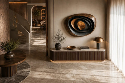 Nested ovoid bronze rings in rust and blue-grey around a polished copper core, on a stone floor.