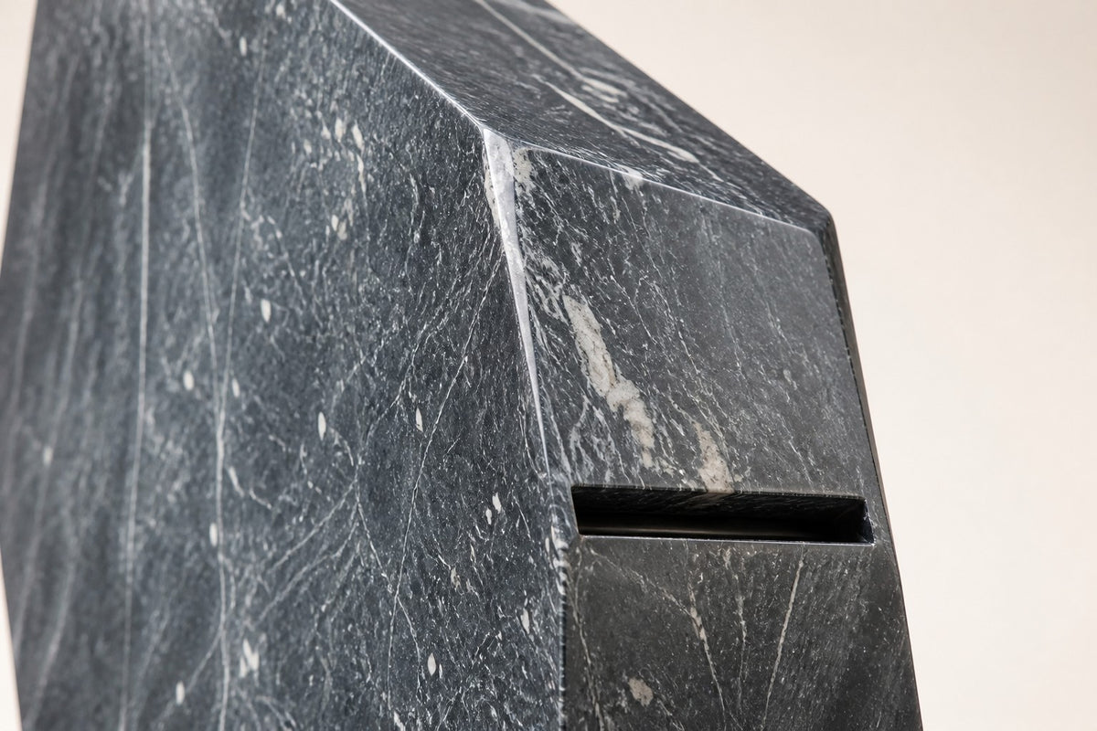 Obelisk Veil — 320 cm dark veined marble obelisk water feature in an oval stone basin, close studio detail of the surface and material
