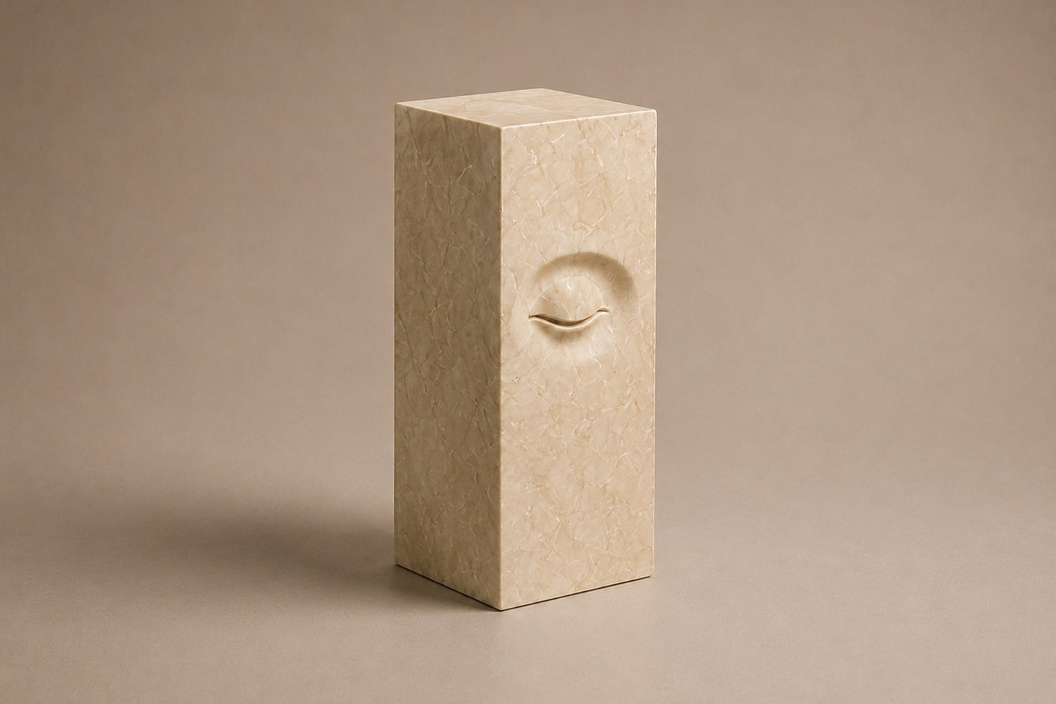 Tall cream Crema Marfil marble pedestal with a closed eye carved in shallow relief on one face.