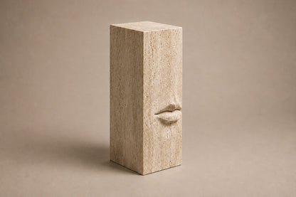 Tall cream travertine pedestal with a mouth carved in relief on one face.