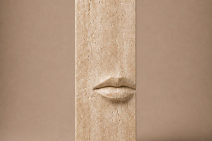 Tall cream travertine pedestal with a mouth carved in relief on one face.