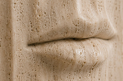 Tall cream travertine pedestal with a mouth carved in relief on one face.