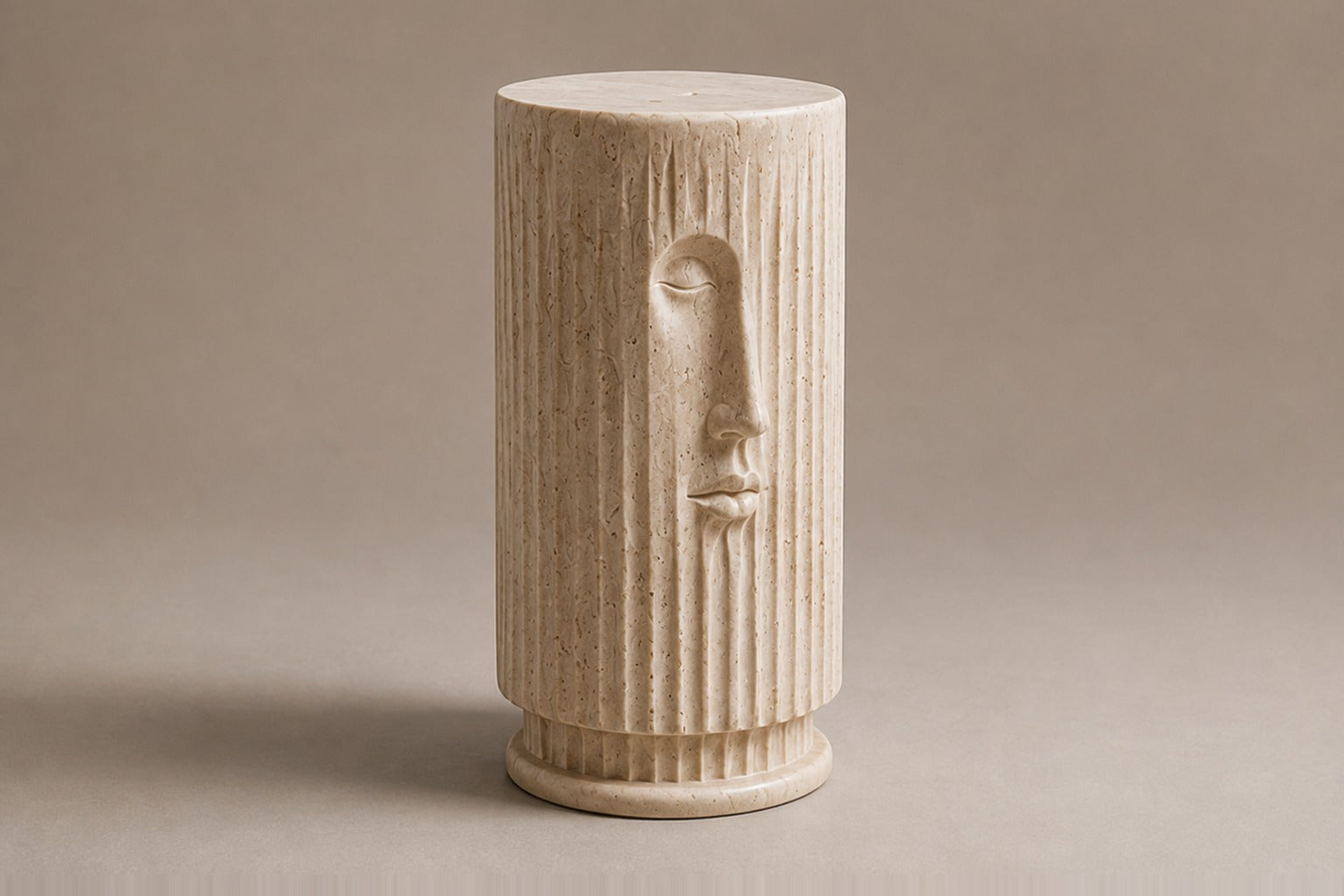Fluted cream travertine drum on a round moulded foot, with a face carved through the flutes.