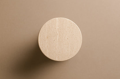 Fluted cream travertine drum on a round moulded foot, with a face carved through the flutes.