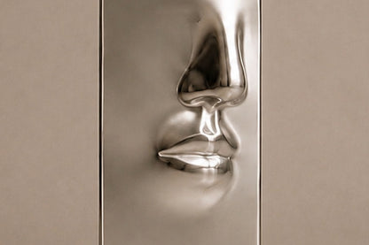 Tall mirror-polished stainless steel pedestal with a nose and mouth formed seamlessly out of one face.