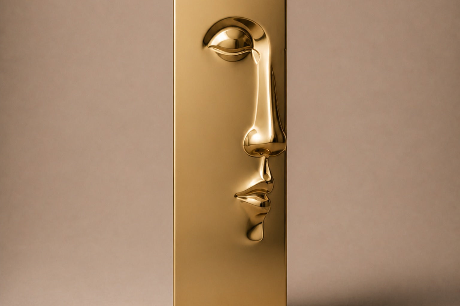Tall gold PVD pedestal with a closed eye, nose and mouth formed seamlessly out of one face.