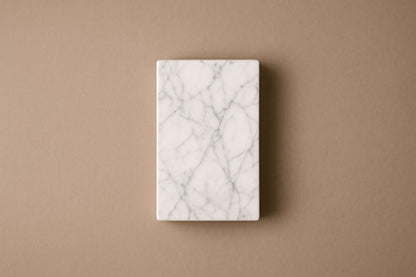 Tall white Carrara marble column carved into a grid of raised cushioned panels.