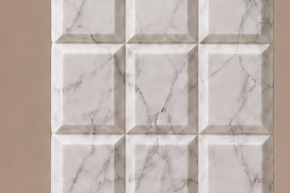 Tall white Carrara marble column carved into a grid of raised cushioned panels.