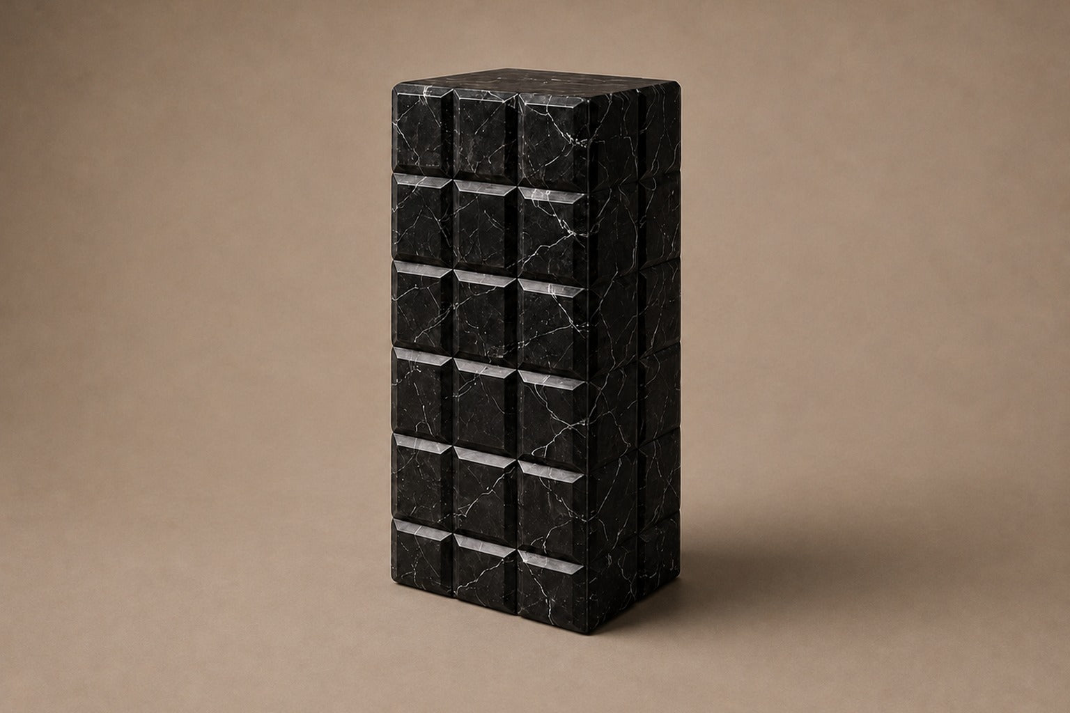 Tall black Nero Marquina marble column carved into a grid of raised cushioned panels.