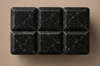 Tall black Nero Marquina marble column carved into a grid of raised cushioned panels.