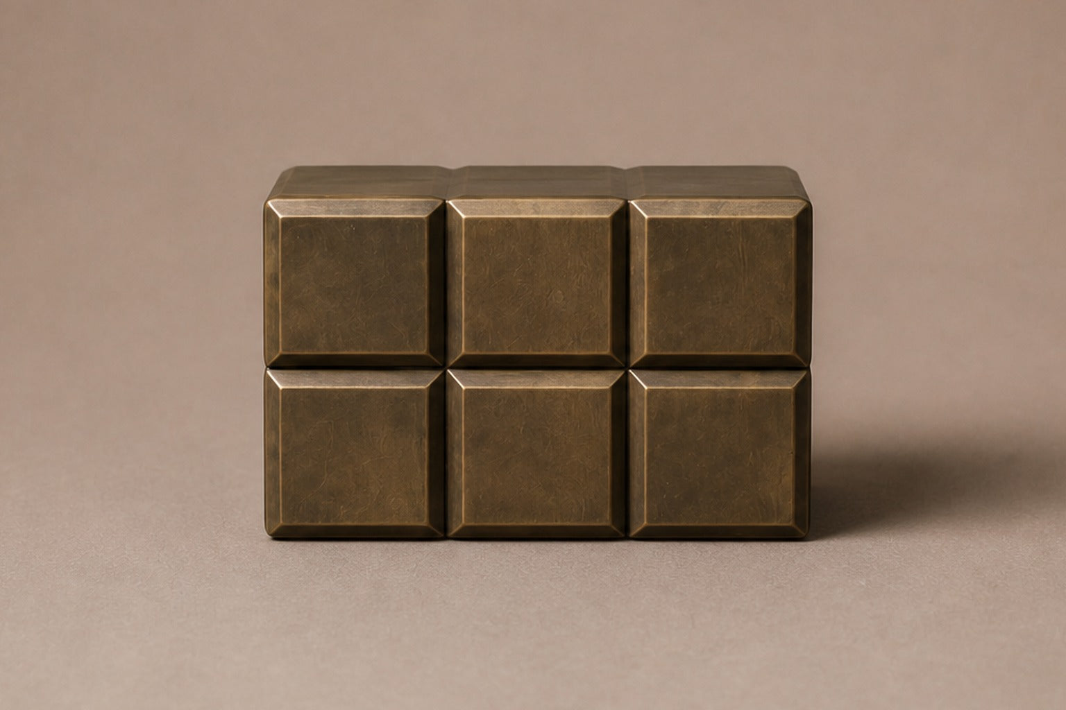 Tall antique bronze column built as a grid of raised cushioned panels.
