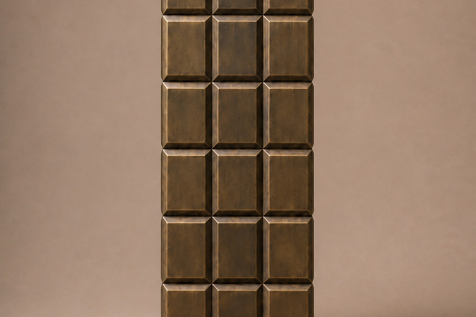 Tall antique bronze column built as a grid of raised cushioned panels.