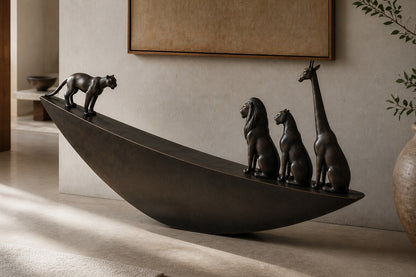 Dark bronze crescent sculpture Quebrada balanced on its curve, three seated forms at the high end and one walking down the fall.