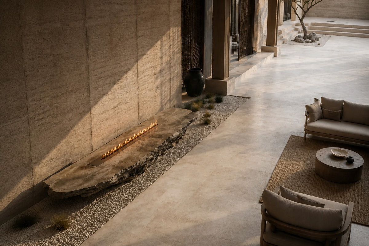 Coral travertine fire table Rimala 220, warm coral and honey, on a pale stone floor.