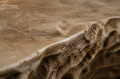 Coral travertine fire table Rimala 220, warm coral and honey, on a pale stone floor.