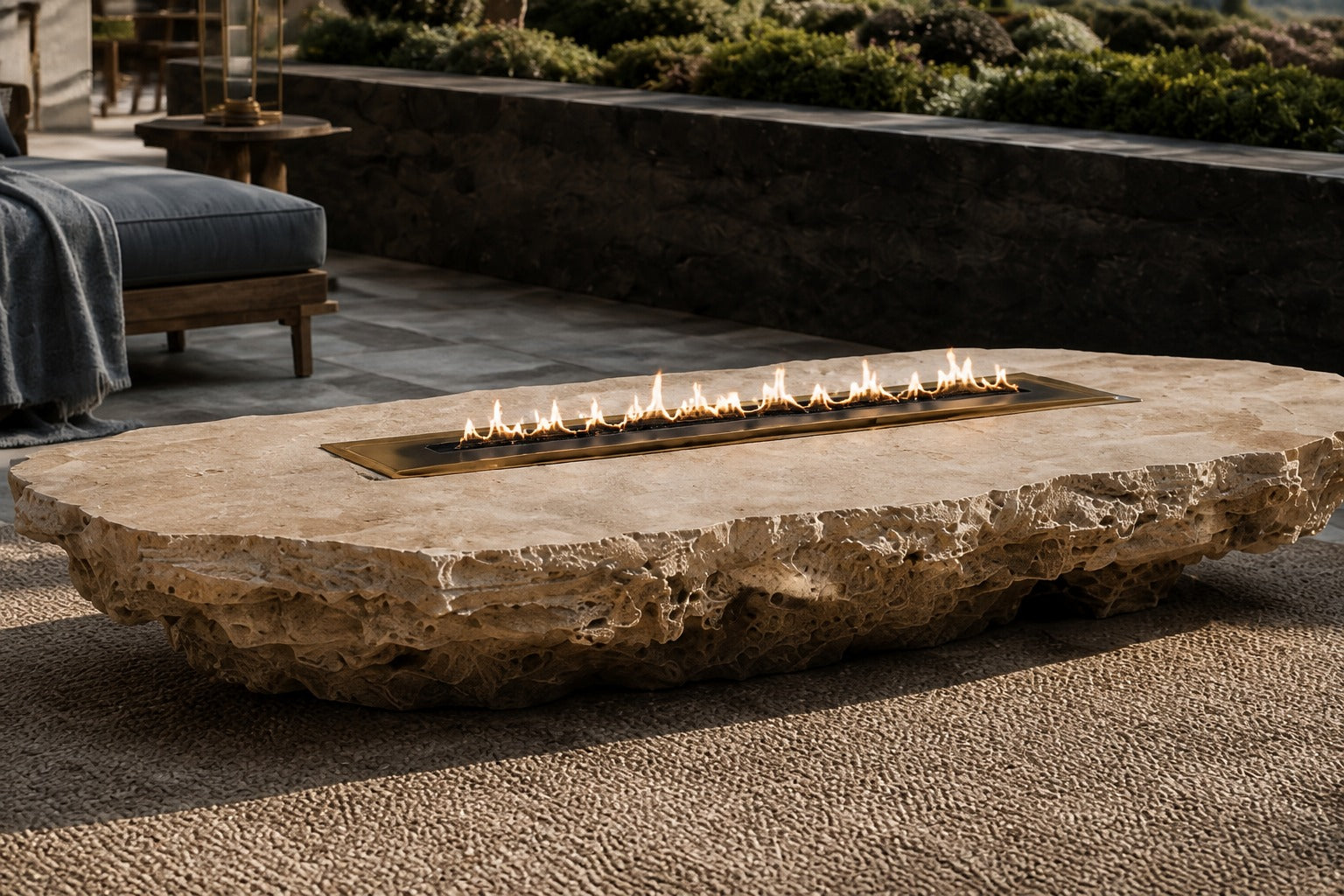 Coral travertine fire table Rimala 220, warm coral and honey, on a pale stone floor.