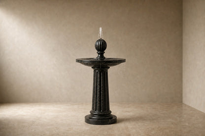 Stone pedestal fountain Sahran Ø65, black with gold veining, on a pale stone floor.