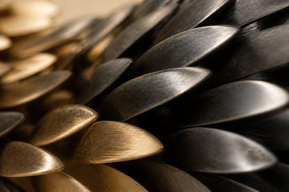 Twisting horizontal spindle clad in pointed scales, gilt on one half and blackened on the other.